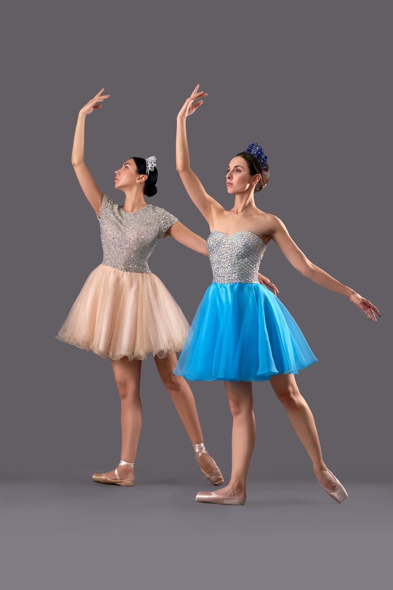 Two ballet dancers mid-pose, arms raised, in sequinned bodices and tulle skirts.